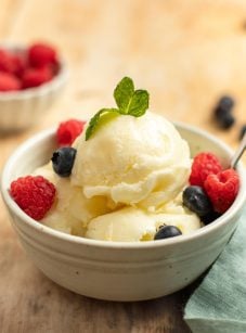 Spoon in a bowl of lemon ice and berries.