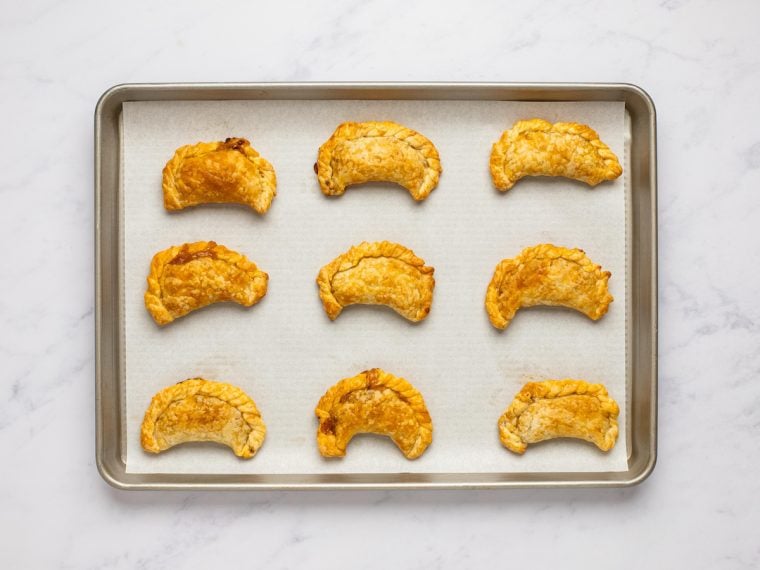 baked empanadas cooling on baking sheet