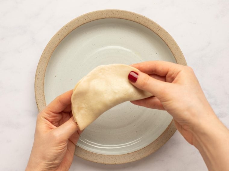 folding wrapper in half over beef and pinching edges to seal