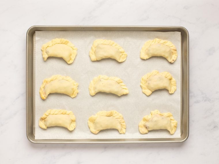 unbaked empanadas on baking sheet