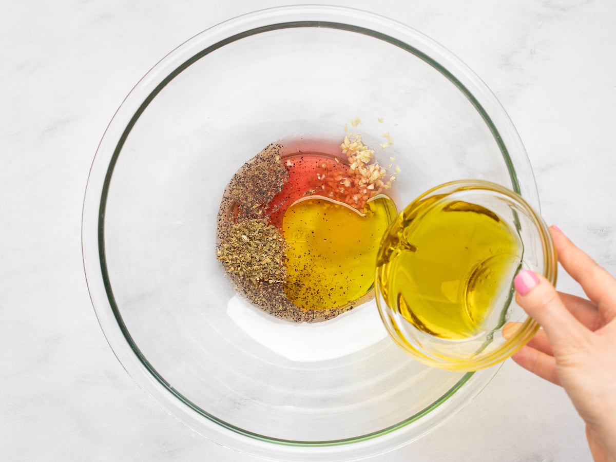 Adding oil to the remaining salad dressing ingredients.