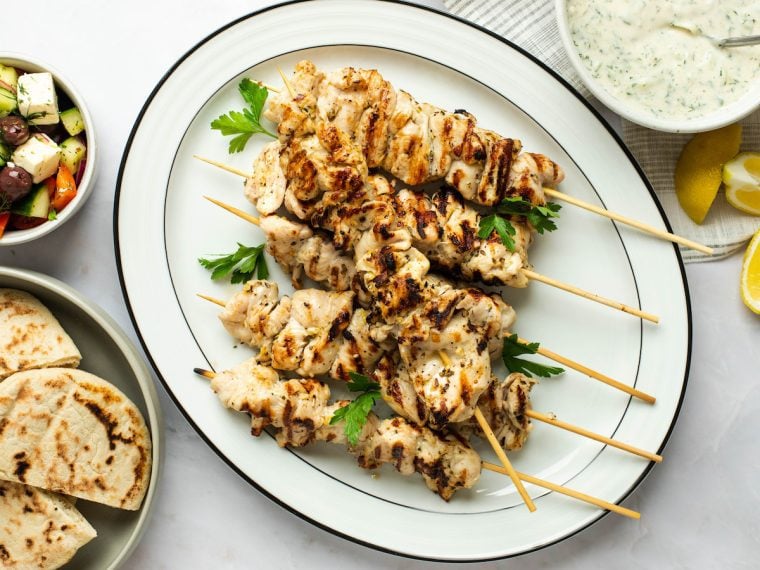 souvlaki on platter with tzatziki sauce, warm pita, and green salad