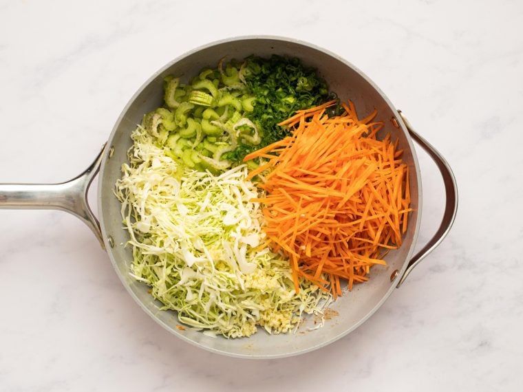 cabbage, celery, carrots, scallions, and garlic added to pan with oil