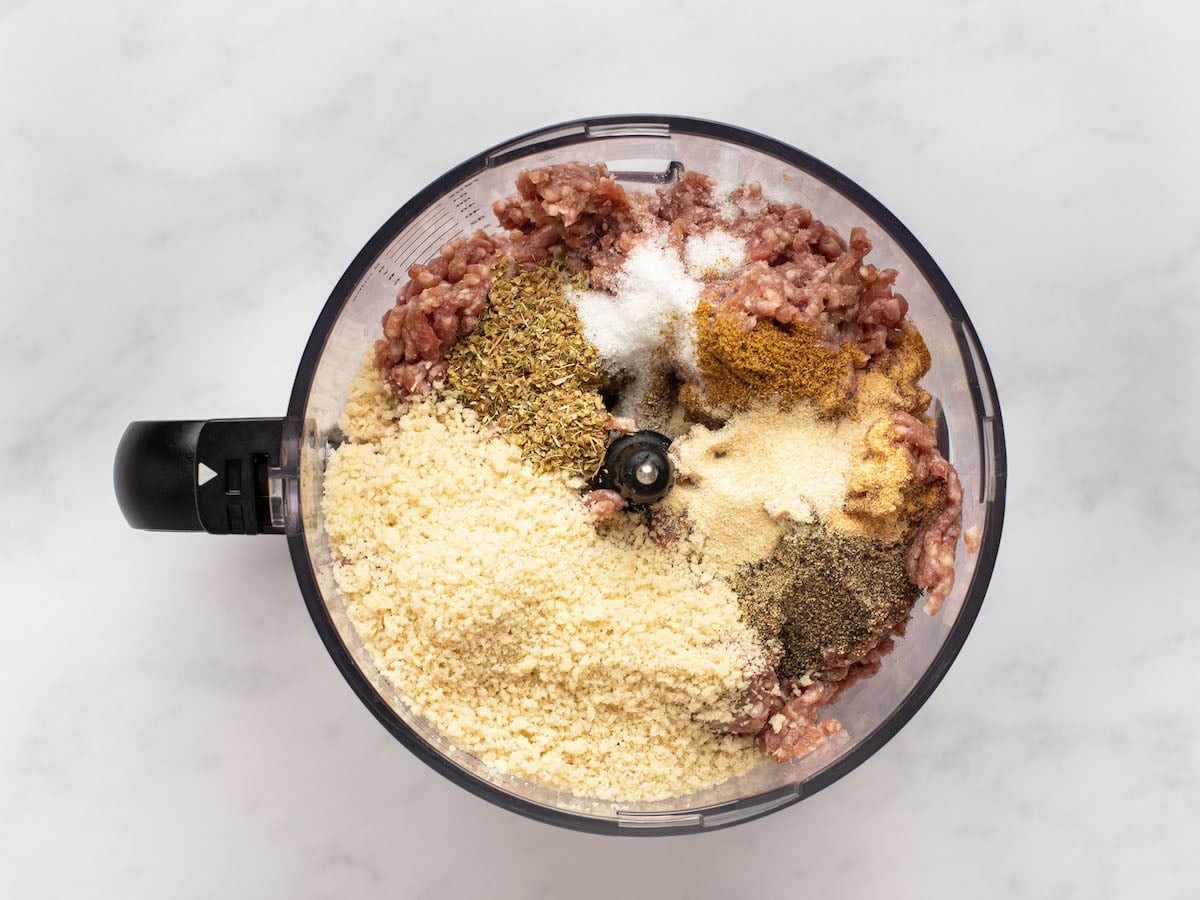 Ingredients to make the gyro meat added to a food processor bowl.