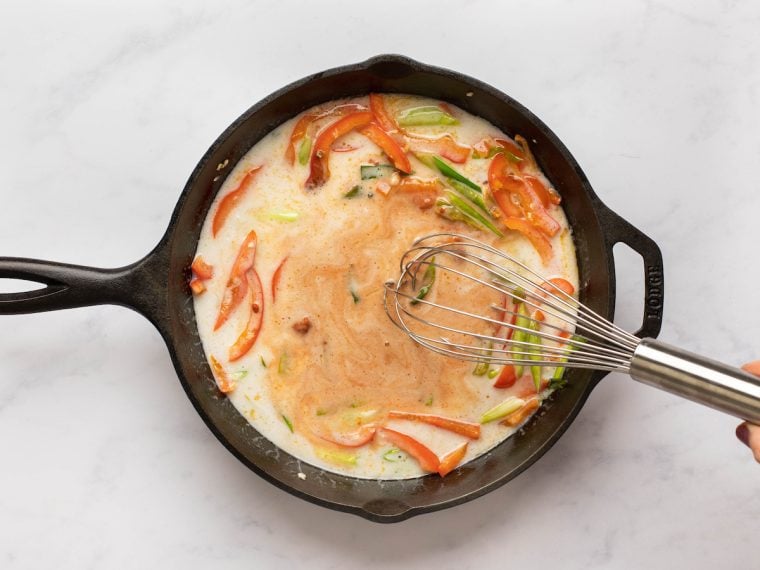 whisking coconut milk, curry paste, fish sauce, and sugar together