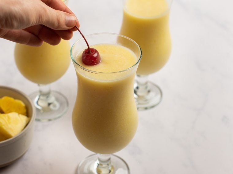 pina coladas being garnished with maraschino cherries