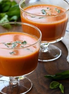 Two stemmed glasses of chilled creamy tomato basil soup.