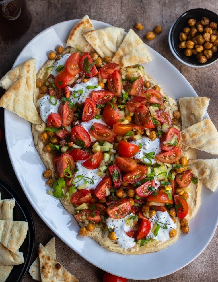 Hummus board with pita, tomatoes, and more.