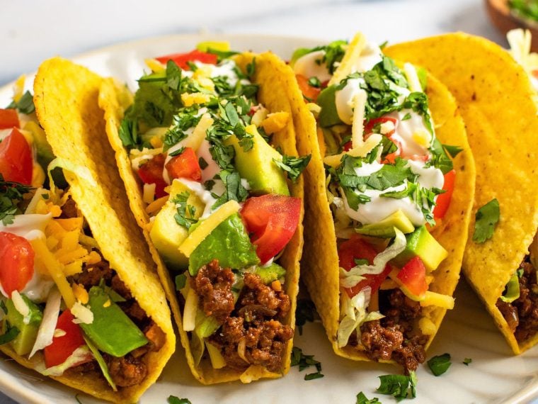 ground beef taco recipe showing stuffed tacos loaded with toppings.