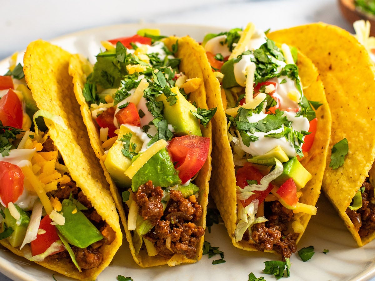 ground beef taco recipe showing stuffed tacos loaded with toppings.