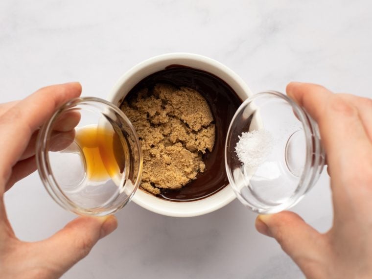 adding sugar, vanilla, and salt to chocolate mixture in mug
