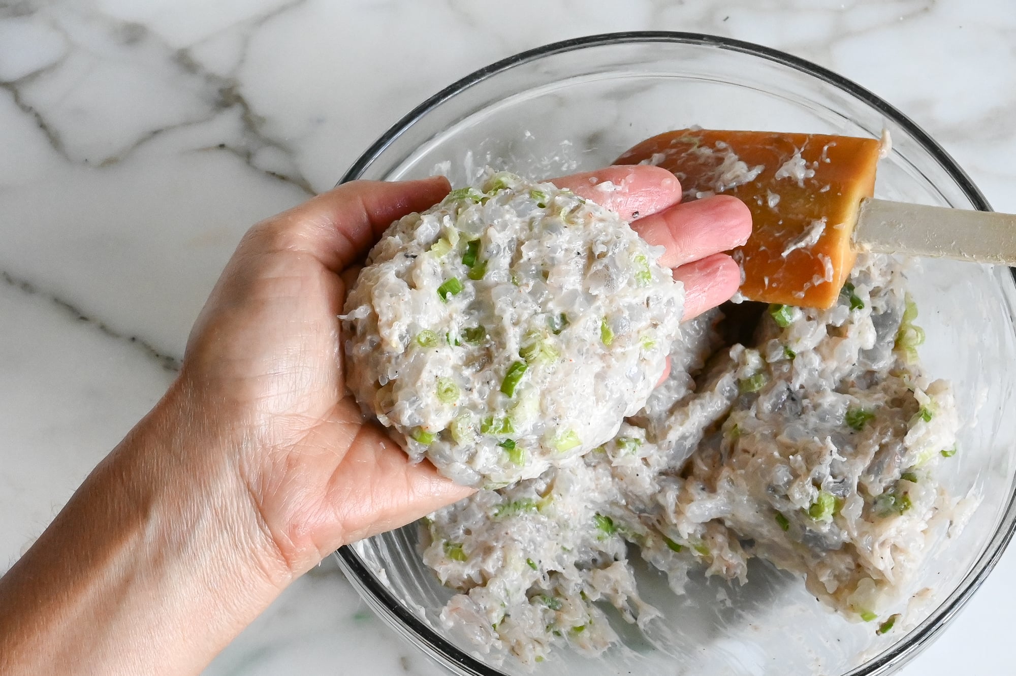 Forming the shrimp burger patties with moistened hands.