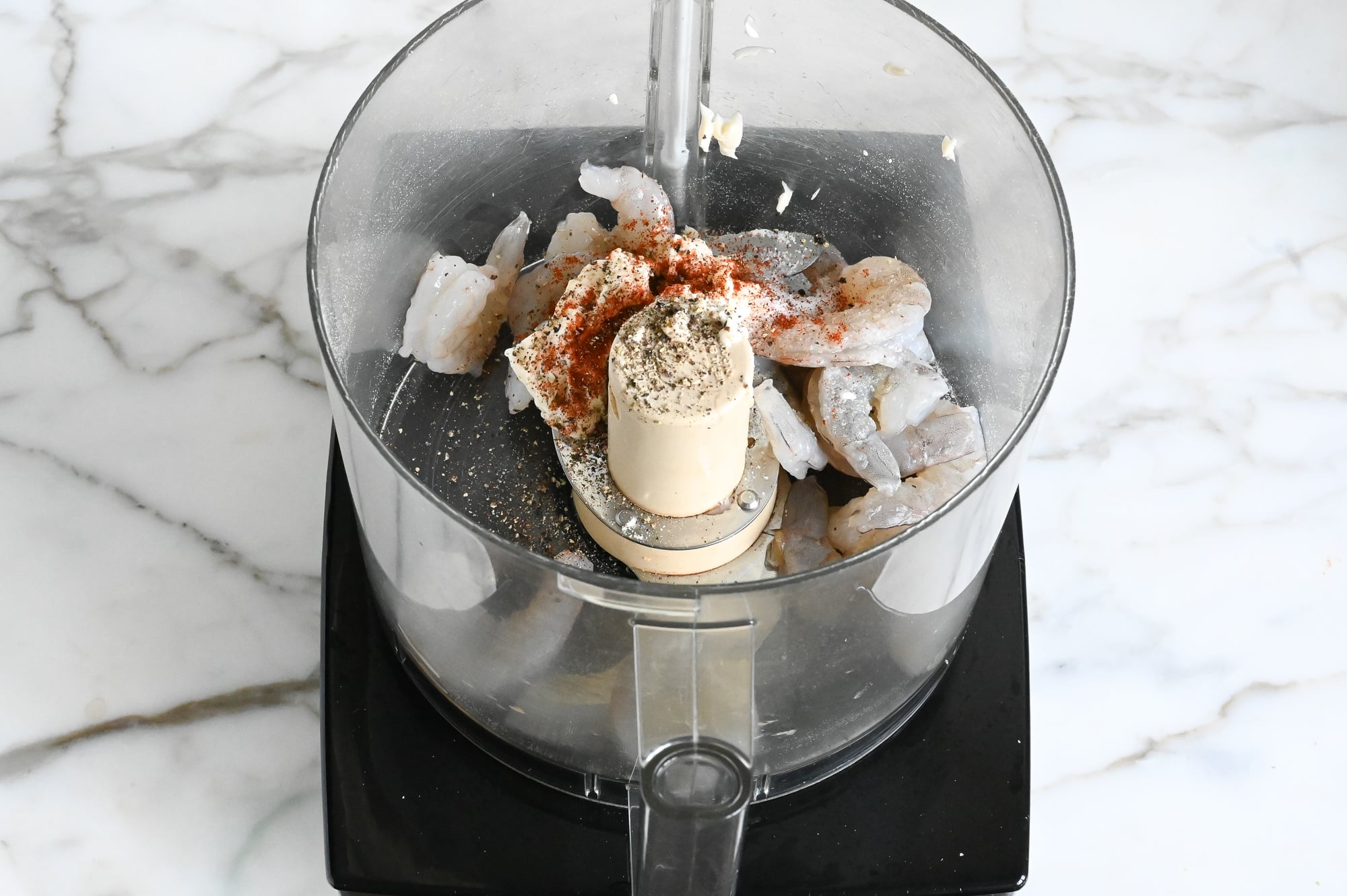 Third of shrimp in food processor with seasoning.