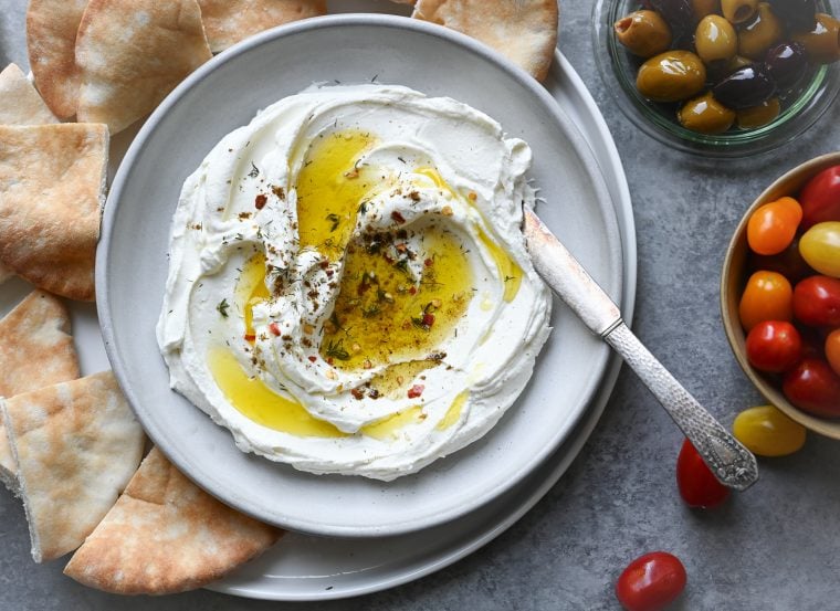 labneh on plate with olive oil, tomatoes and olives on the side