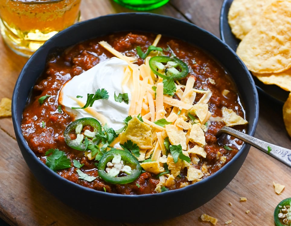 Bowl of chili with toppings and tortilla chips.