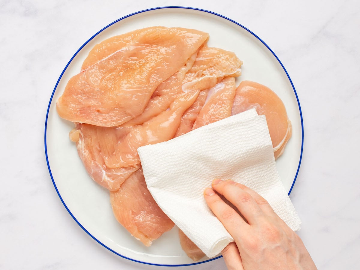 patting chicken dry with paper towels