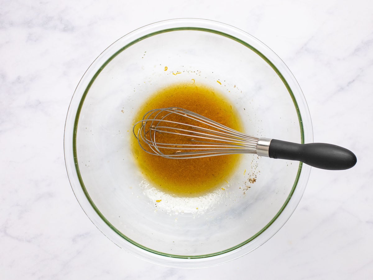 whisking orange zest, orange juice, oil, vinegar, honey, mustard, pepper, and salt