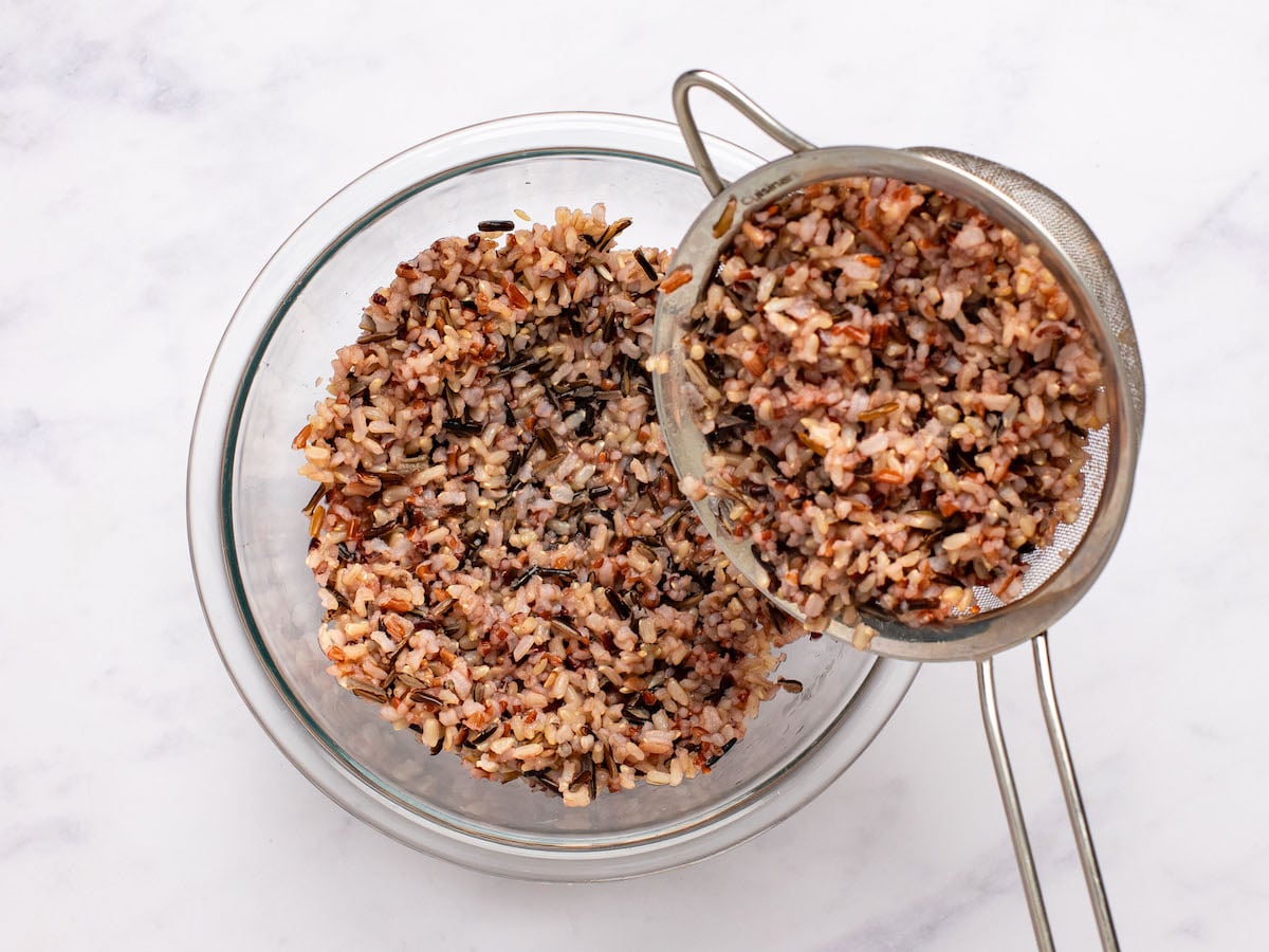 adding rice to bowl with dressing