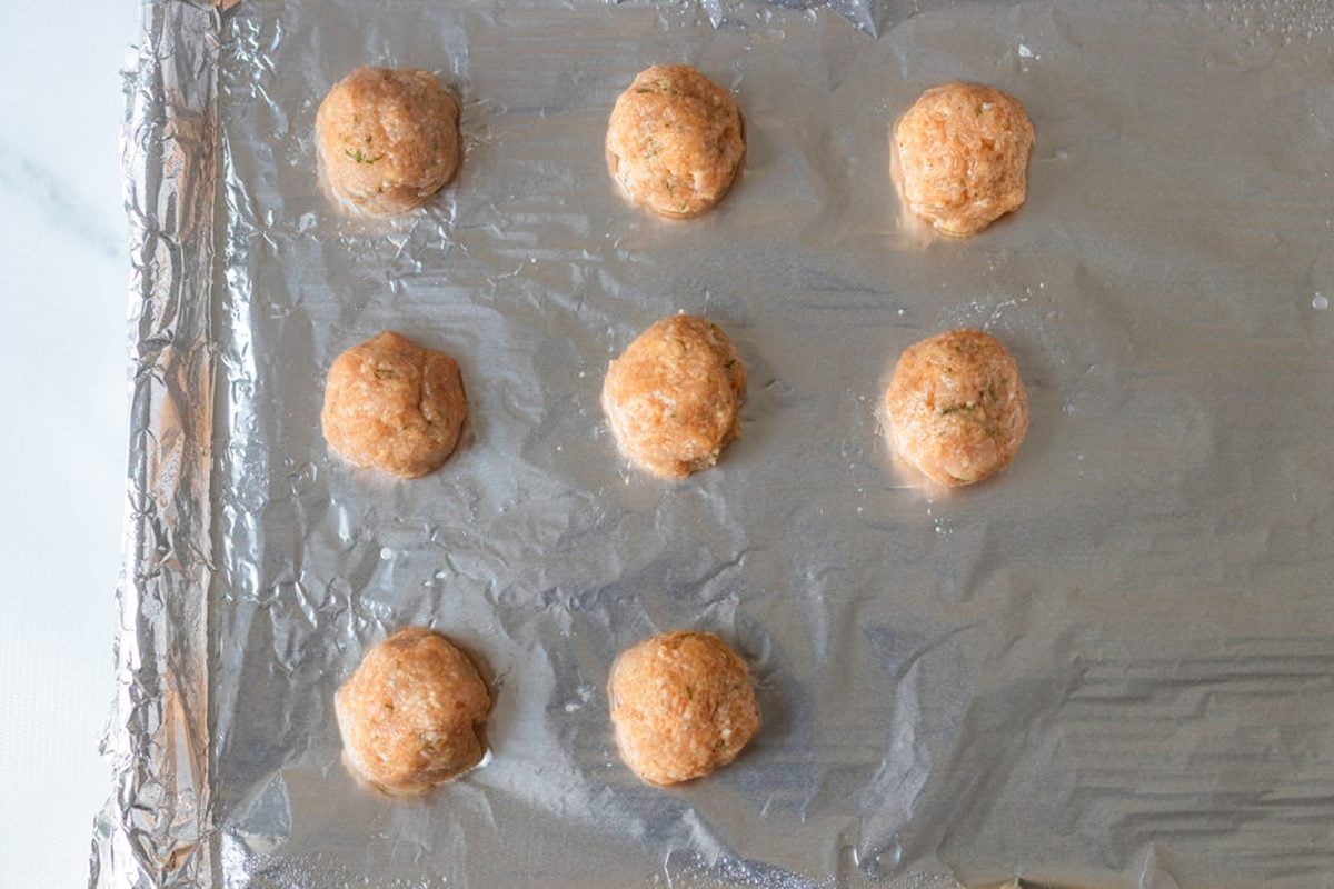 Uncooked meatball on aluminum foil.