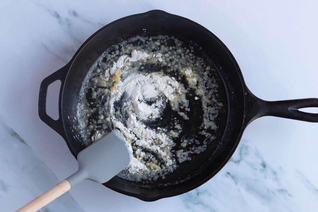 adding flour to pan with shallots.