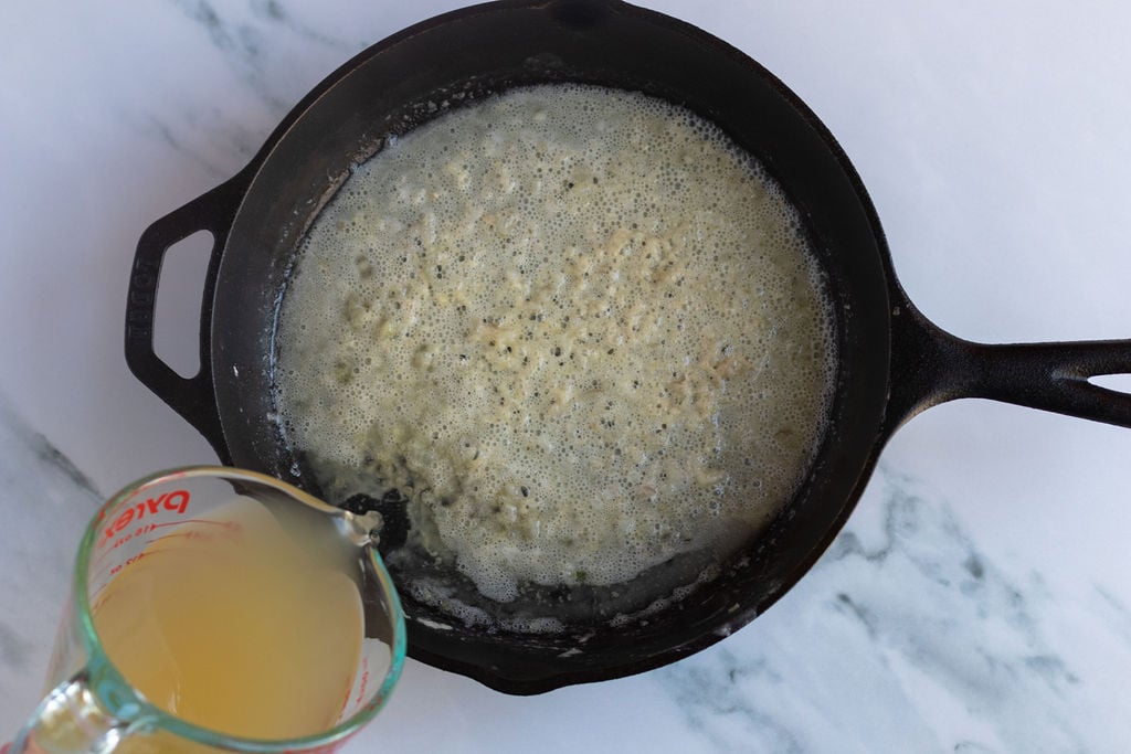 adding chicken stock to skillet