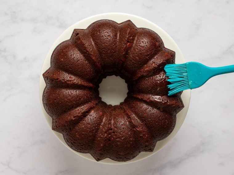 brushing remaining glaze on top of cake