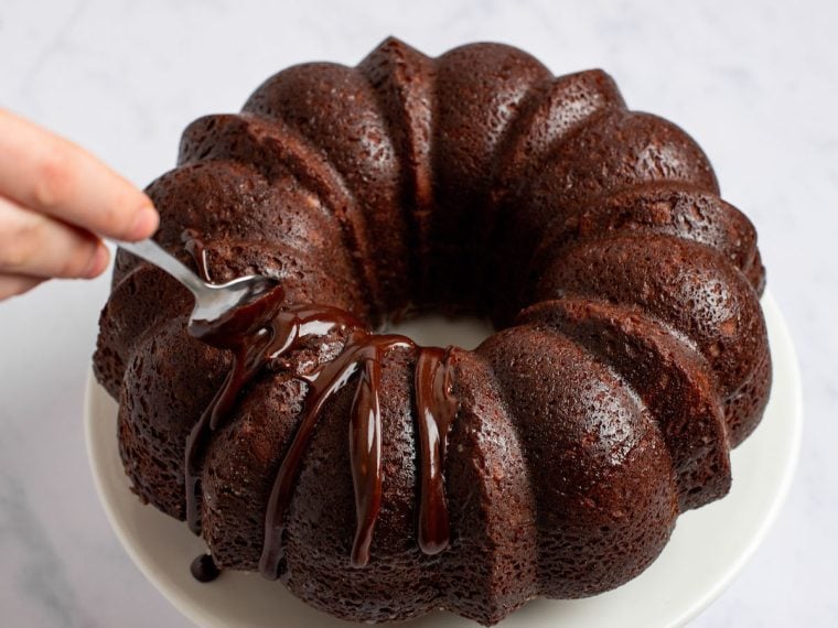 drizzling glaze over cake with spoon