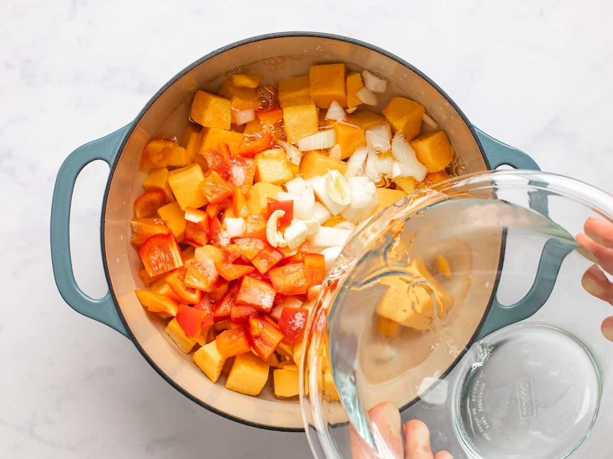 Water pouring into a pot of chopped vegetables.