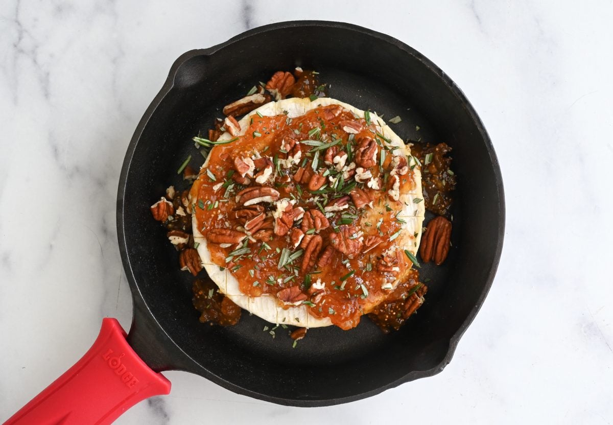 brie with jam, pecans, and rosemary in skillet