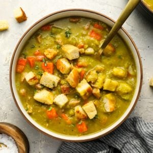 Bowl of split pea soup topped with croutons.