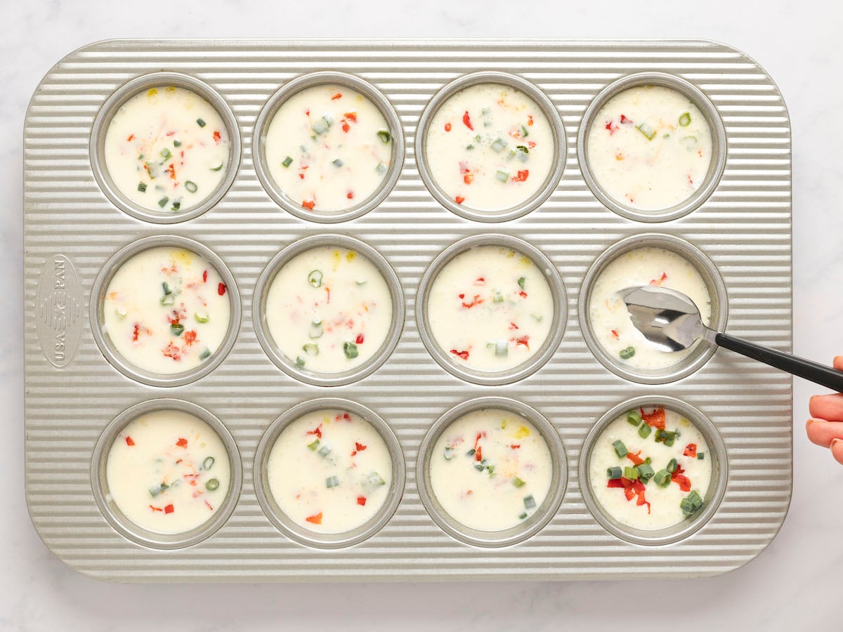 pressing peppers and scallions into batter with spoon