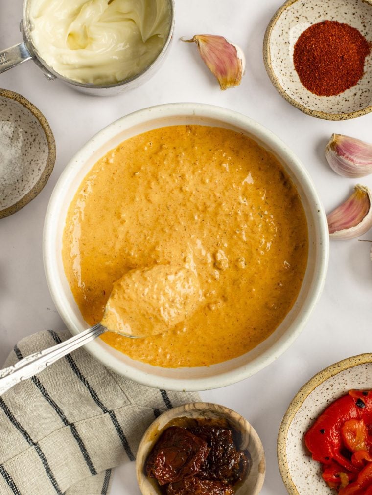 sun-dried tomato and red pepper aioli in a bowl with ingredients surrounding it