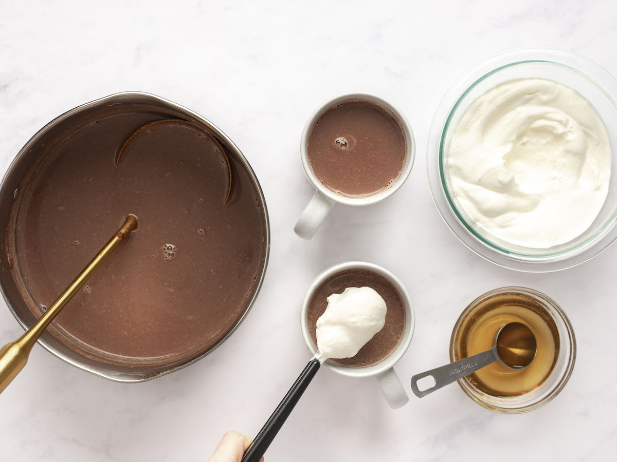 hot chocolate in mugs with whiskey added and whipped cream on top.