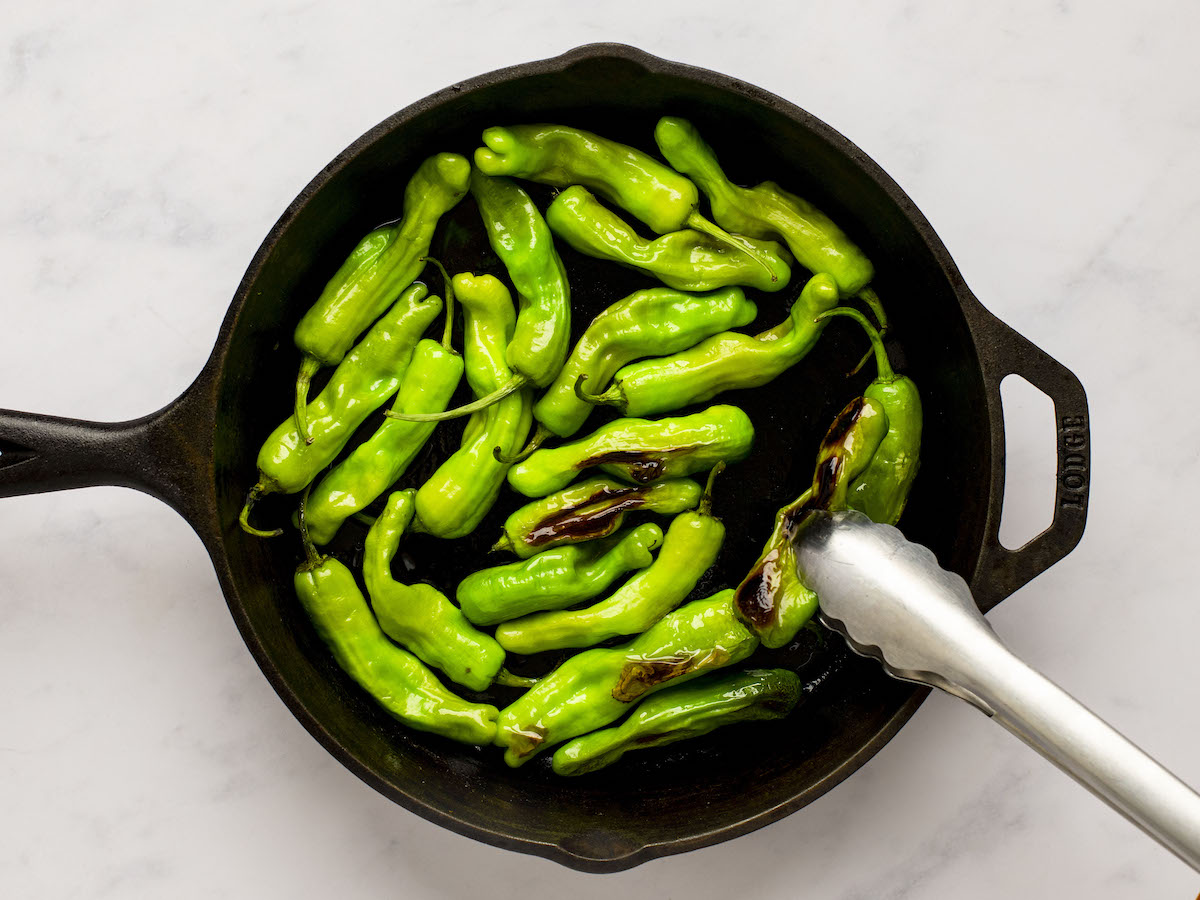 turning shishito peppers with tongs as they blister