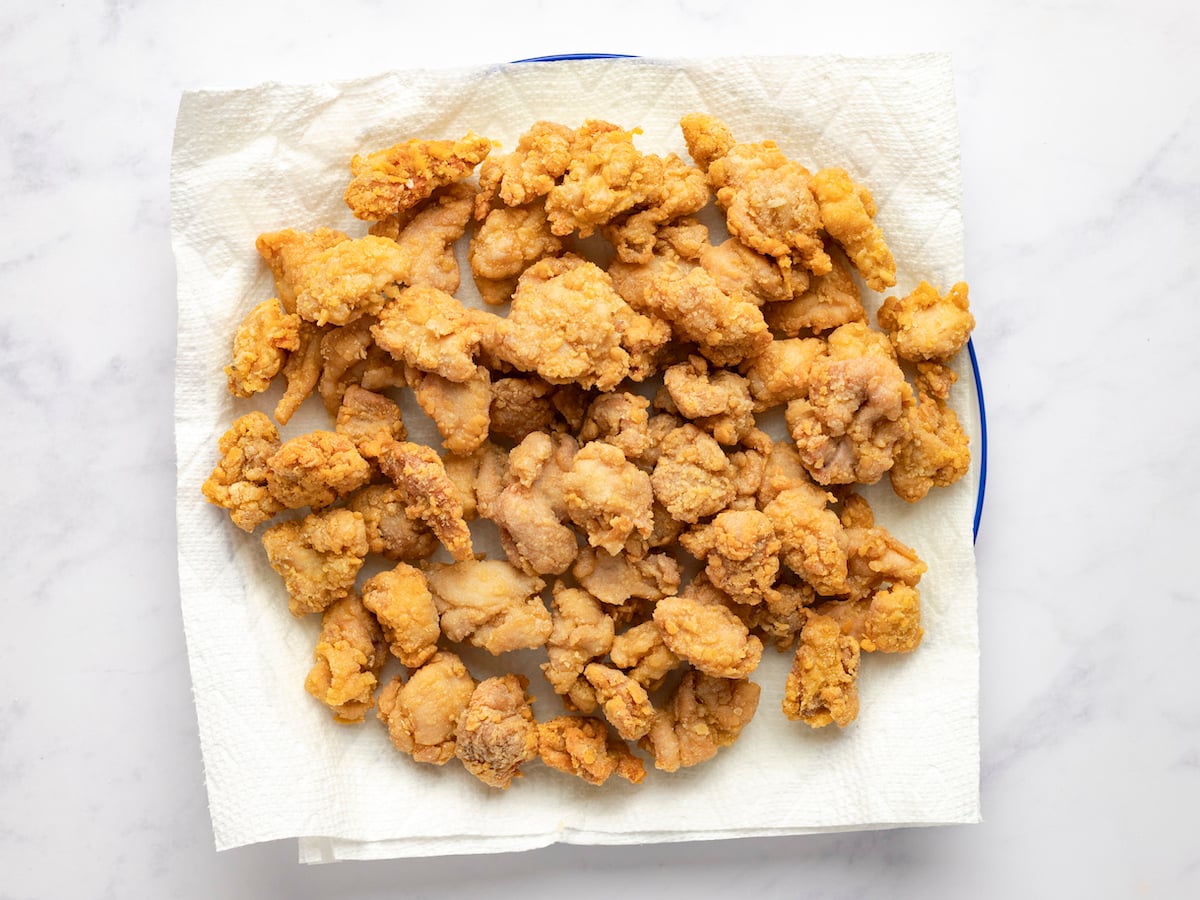 draining golden chicken pieces on paper towel-lined plate
