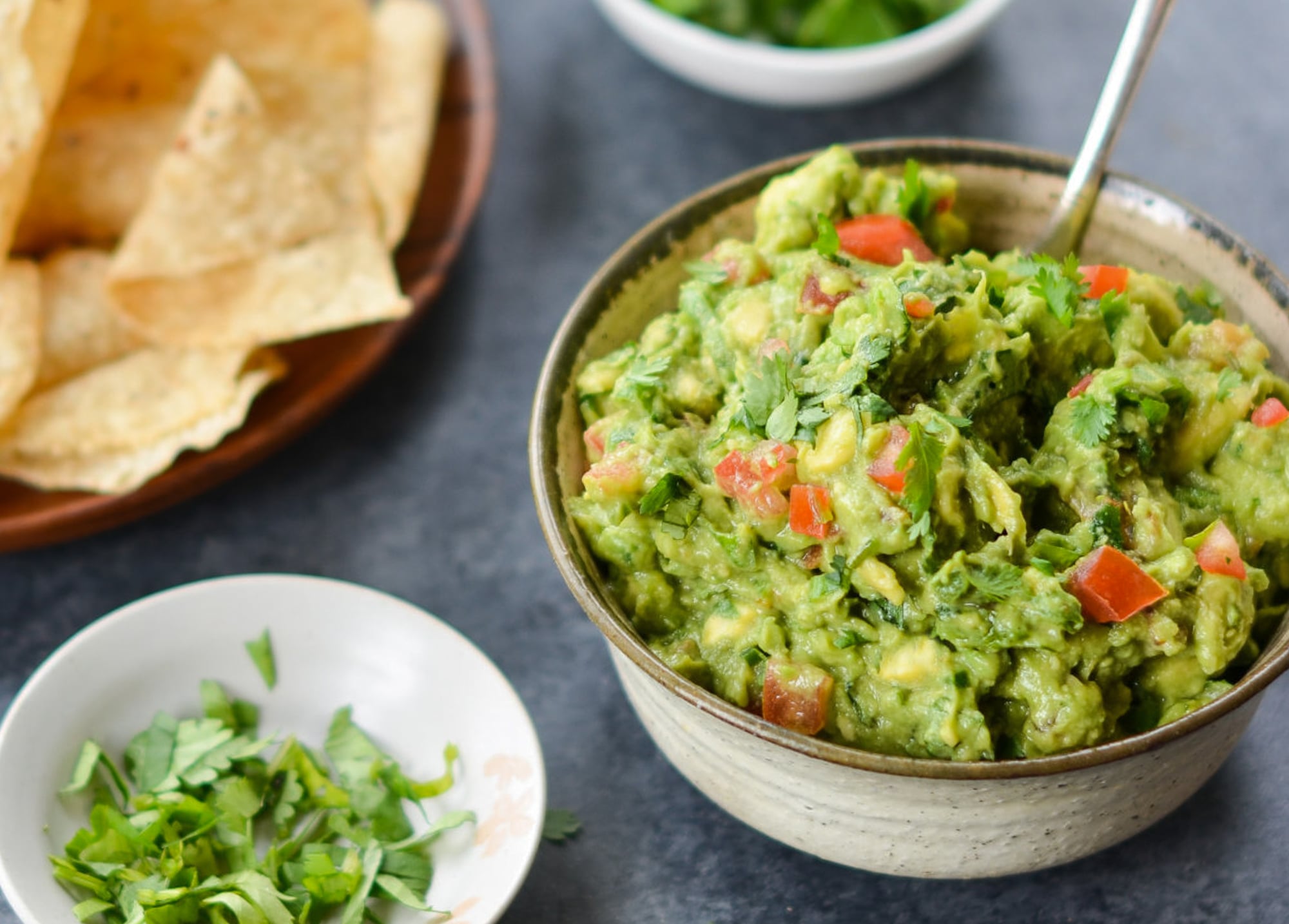 Bowl of guacamole with chips on a table.