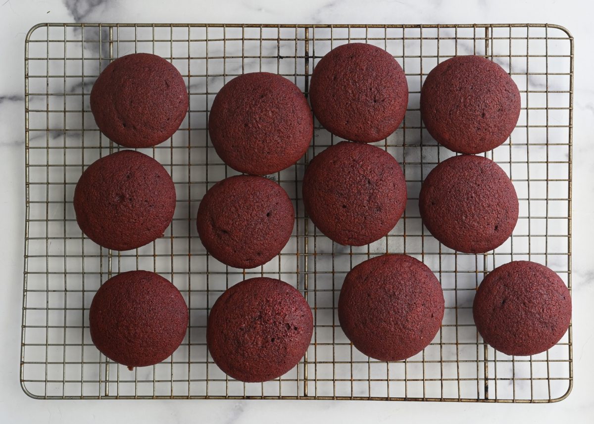 red velvet cupcakes cooling on rack.