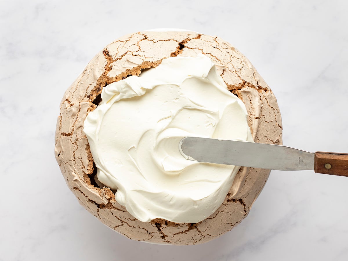 spreading mascarpone cream onto pavlova.