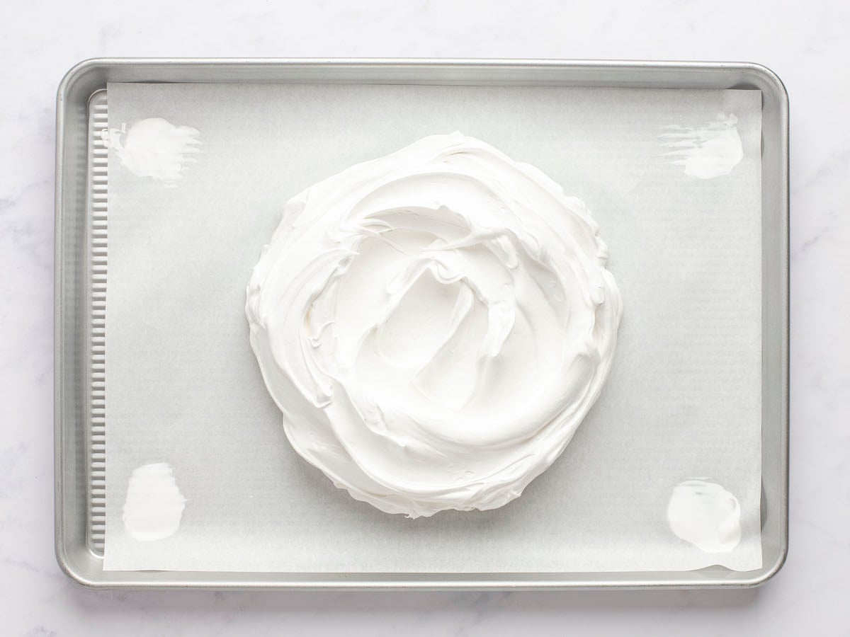 Meringue mounded onto parchment-lined baking sheet.