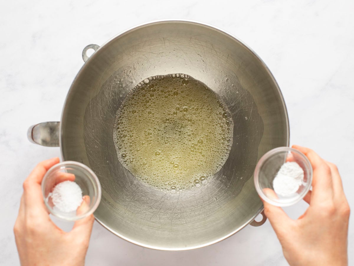 Adding salt and cream of tartar to mixing bowl with beaten egg whites.