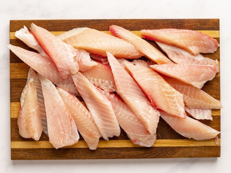 raw tilapia fingers on cutting board