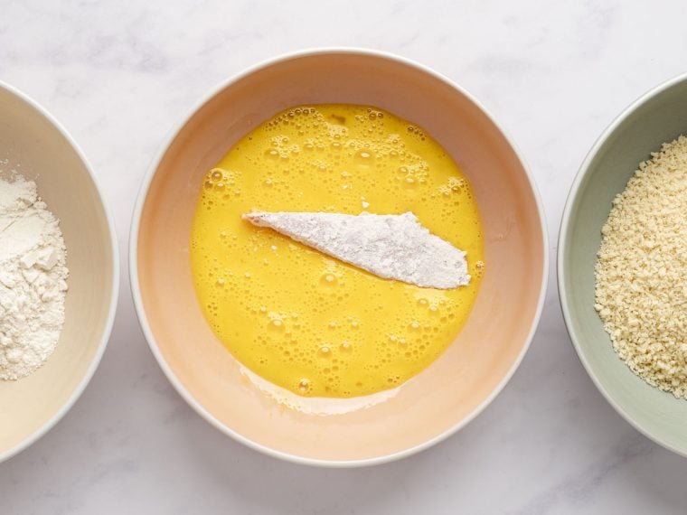 dipping the flour-coated fish in the egg mixture
