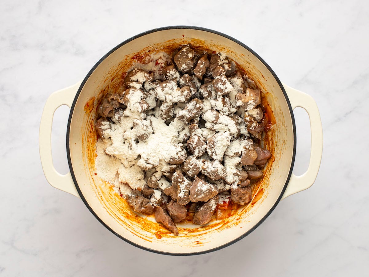 adding flour and lamb to Dutch oven
