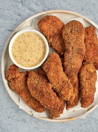 pecan crusted chicken tenders on plate with honey mustard sauce