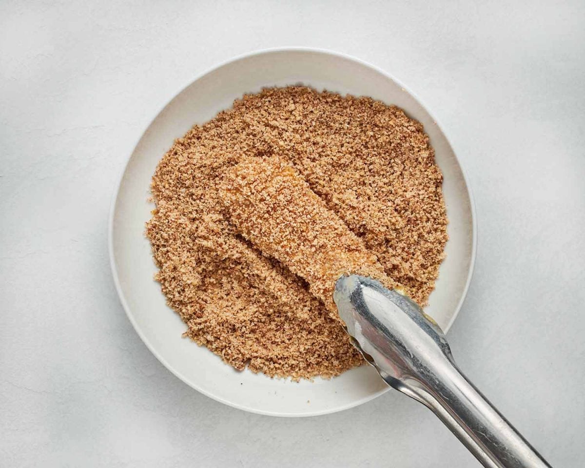 coating the chicken with the pecan breading.