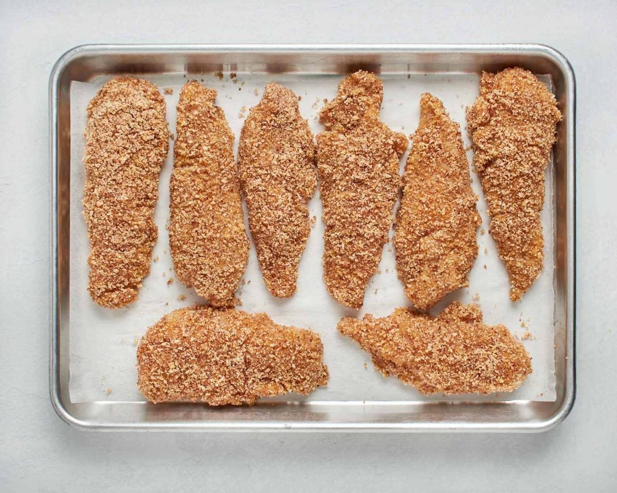 breaded chicken tenders on baking sheet