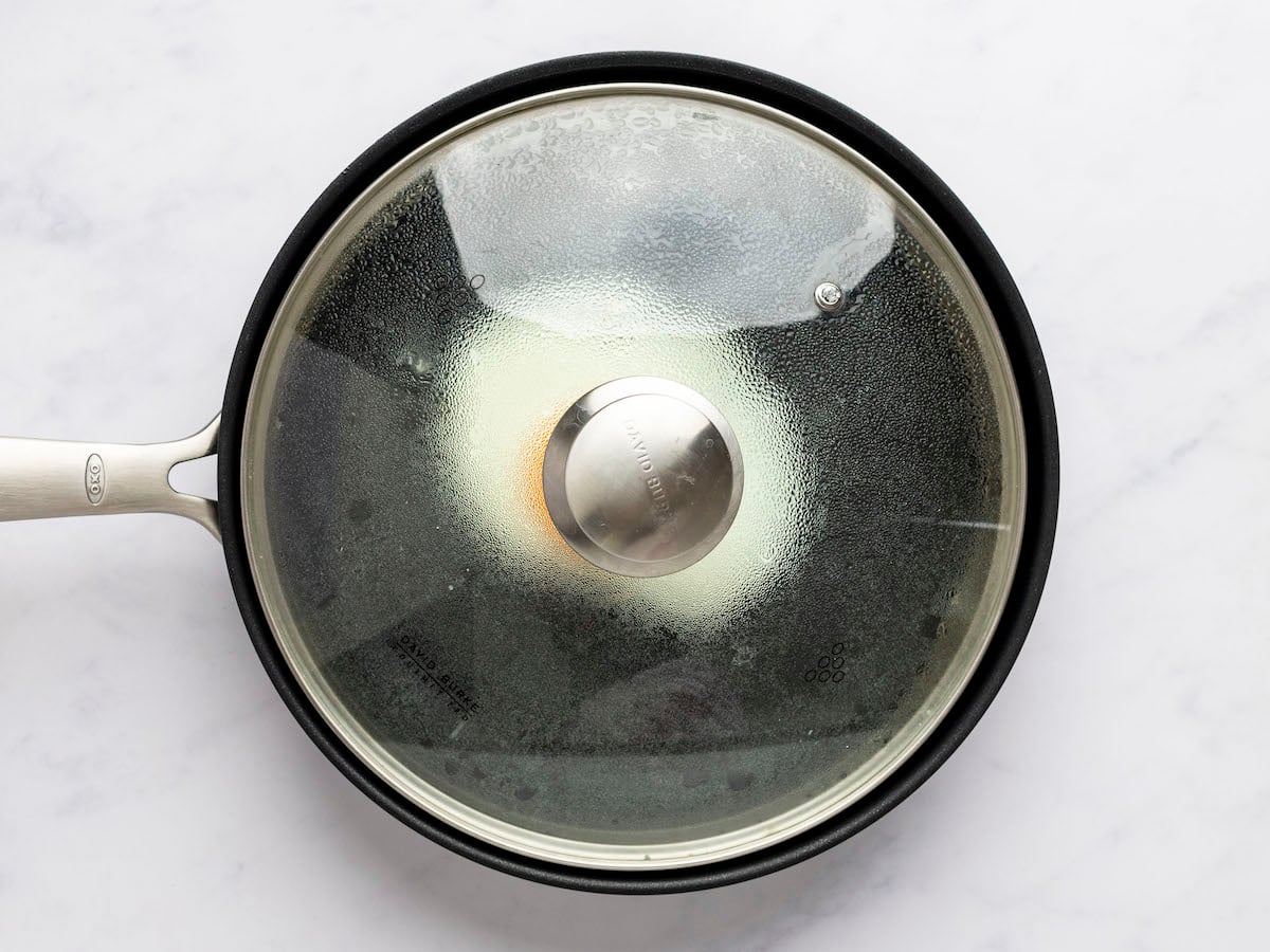 egg cooking in medium non-stick pan covered with lid