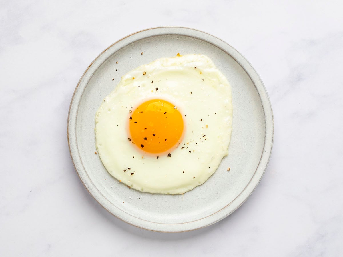 sunny side up egg on white plate with salt and pepper