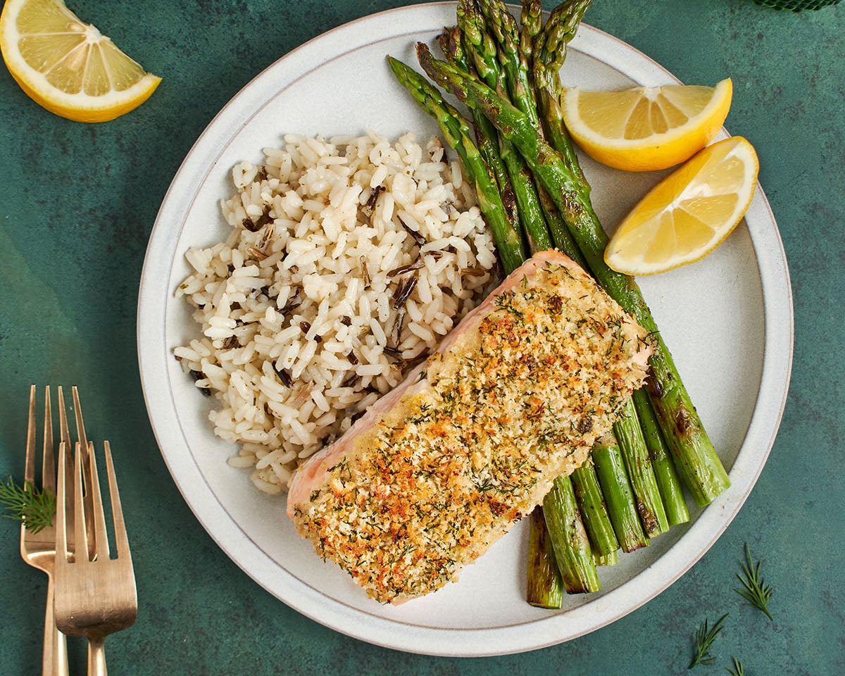 Baked salmon on plate with asparagus, rice, and lemon wedges.