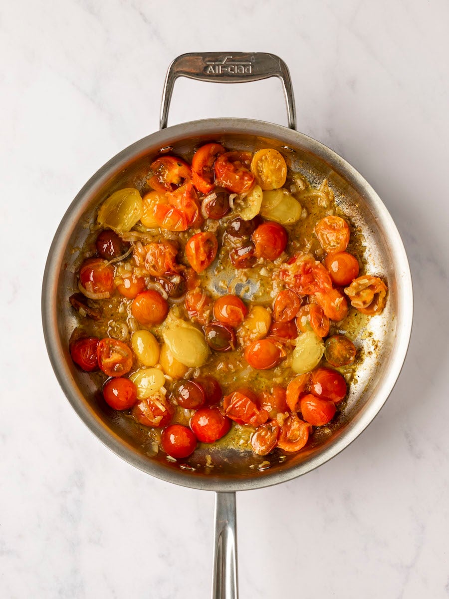 tomatoes starting to soften and burst in large pan with garlic and shallots